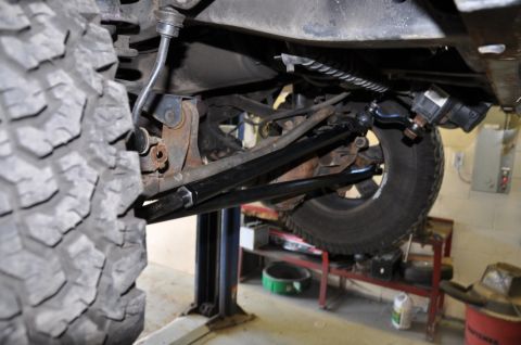 1996 Ford Bronco - Close-up of the suspension and tire assembly of a vehicle being worked on in a garage.