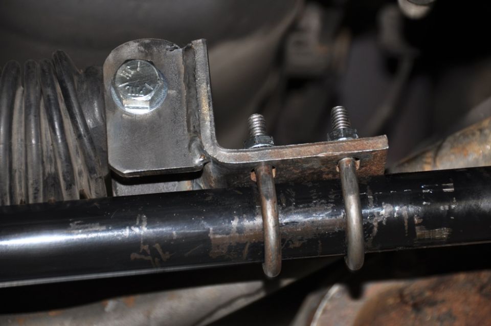 Close-up of a metal bracket bolted to a black bar, with a rubber boot visible