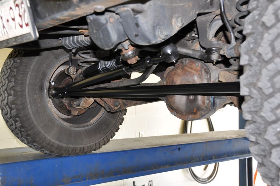 Undercarriage of a vehicle on a lift, showing suspension and differential