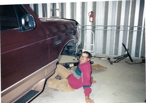 1996 Ford Bronco - A man works on the underside of a maroon 1996 Ford Bronco in a garage.
