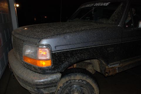 1995 Ford Bronco - A dirty black Ford Bronco is parked in a garage at night, viewed from the front-right.