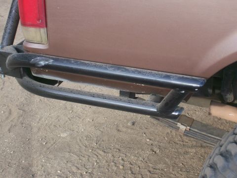 1993 Ford Bronco - Close-up of the rear of a brown SUV, showing a custom bumper and suspension components.