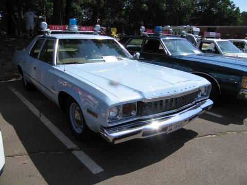 1991 Ford LTD Crown Victoria - light-blue Plymouth Fury State Police sedan with roof lights, parked in a row of police cars at a show.
