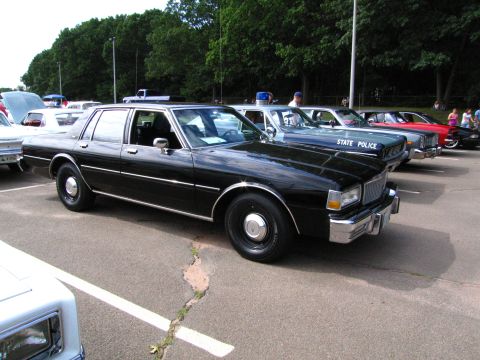 1991 Ford LTD Crown Victoria - Front three-quarter view of a black Chevrolet Caprice marked STATE POLICE, parked among other classic cars at a show.