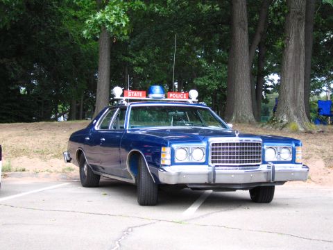 1991 Ford LTD Crown Victoria - Blue 1970s Ford full-size four-door sedan restored as a state police cruiser, photographed from the front three-quarter in a paved lot back…
