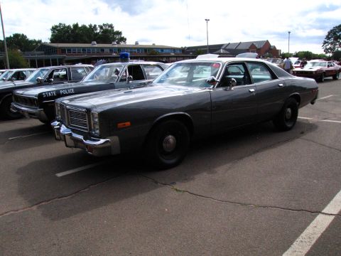 1991 Ford LTD Crown Victoria - gray late-1970s Dodge full-size sedan parked beside a black STATE POLICE cruiser in a show parking lot.