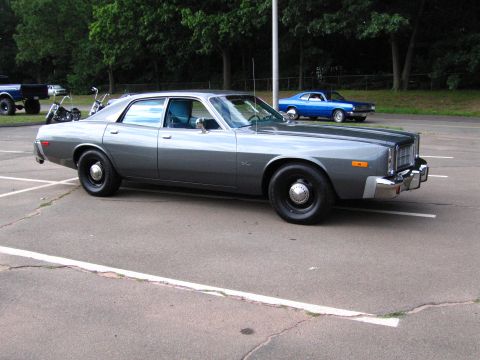 1991 Ford LTD Crown Victoria - gray 1970s Plymouth four-door sedan with black steel wheels parked alone in an empty paved lot.