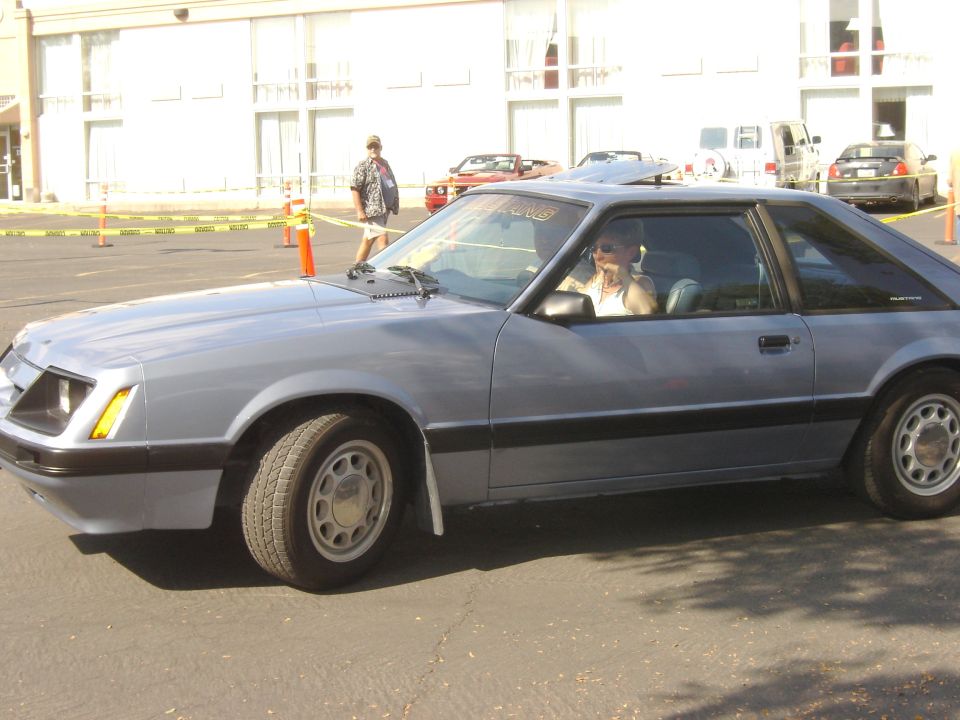 Gray coupe with a sunroof and a person driving, seen from the side