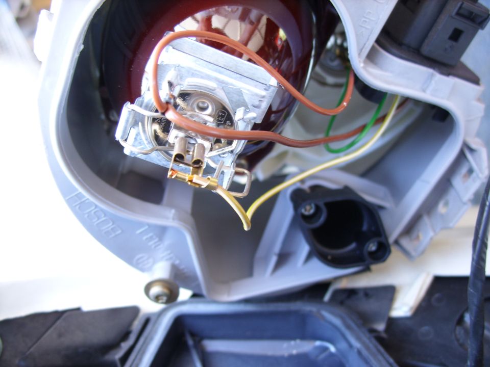 Rear of a headlight housing with bulb retaining clip and brown, yellow and green wiring