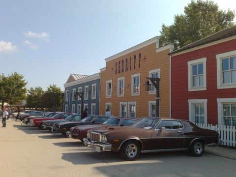 1991 Ford LTD Crown Victoria - A row of vintage cars are parked in front of a western-themed street scene with a Sheriff's building.