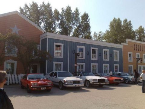1991 Ford LTD Crown Victoria - A row of cars are parked in front of buildings designed to look like an old western town.