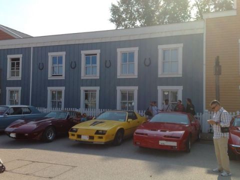 1991 Ford LTD Crown Victoria - Several classic sports cars are lined up in front of a building with a distinctive blue facade and horseshoe decorations.