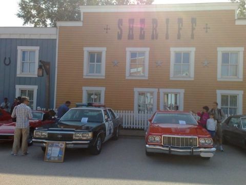 1991 Ford LTD Crown Victoria - A red 1979 Ford LTD is parked in front of a sheriff's building, alongside a police car.