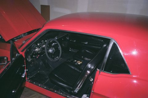 1967 Ford Mustang - Interior view of a red 1967 Ford Mustang, showing the black seats, dashboard, and steering wheel.