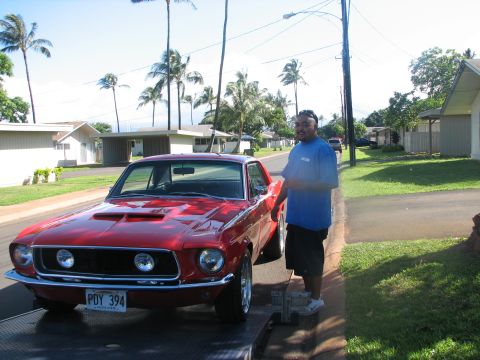 1967 Ford Mustang - A red 1967 Ford Mustang coupe is shown on a trailer, a distinctive hood scoop and dual headlights.