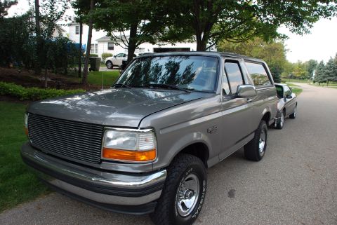 1995 Ford Bronco - Gray 1995 Ford Bronco parked curbside with another vehicle visible behind it.
