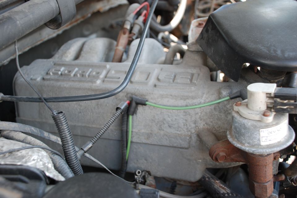 Close-up of an engine intake manifold with some wiring. Text on the manifold is partially visible