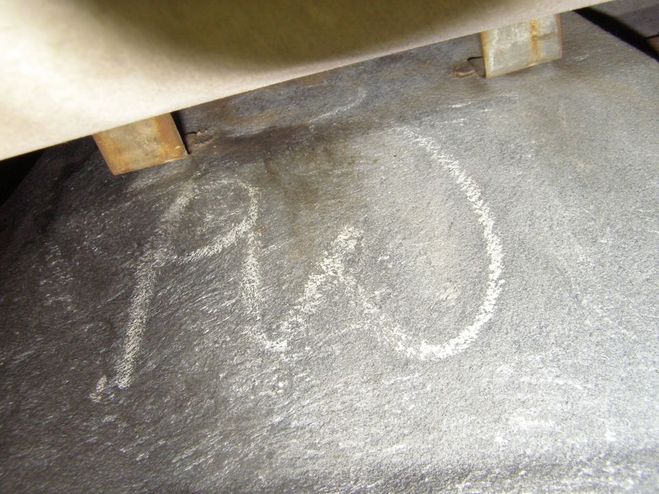 Chalk writing reading 'PO' on a dusty concrete garage floor