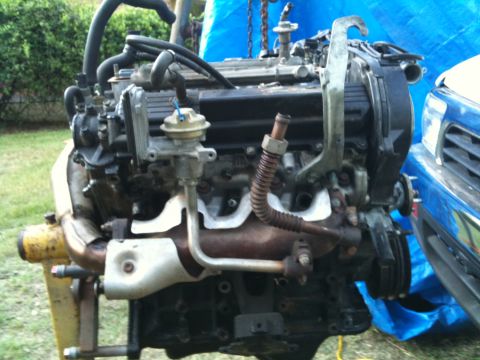 1993 Toyota 4Runner - Engine assembly with various hoses and components, partially obscured by a blue tarp and vehicle fender.