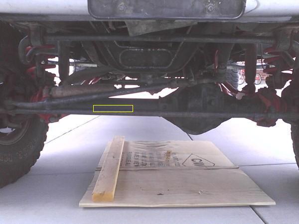 Underside front axle and steering linkage of a lifted truck with a yellow highlight box