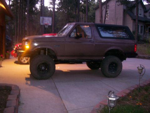 1993 Ford Bronco - Lifted 1993 Ford Bronco with oversized tires sits on a paved driveway.
