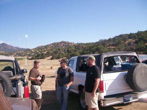 1993 Ford Bronco - A group of friends gathered around a 1993 Ford Bronco in a scenic, rocky outdoor area.