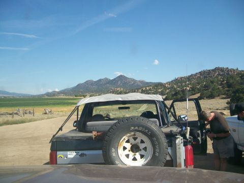 1993 Ford Bronco - A gray Ford Bronco with a soft top is parked on a dirt road with mountains in the background.