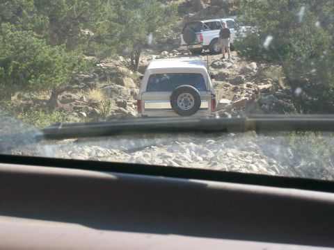 1993 Ford Bronco - Two SUVs navigate a challenging, rocky trail under a clear sky.