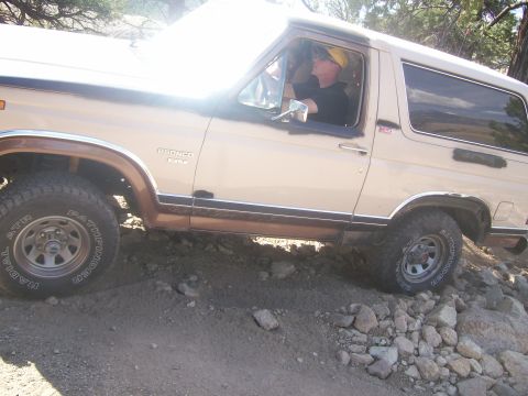 1993 Ford Bronco - A tan 1987 Ford Bronco navigates a challenging rocky terrain off-road.