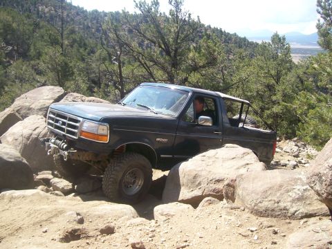 1993 Ford Bronco - A 1993 Ford Bronco tackles a challenging off-road trail with large rocks.