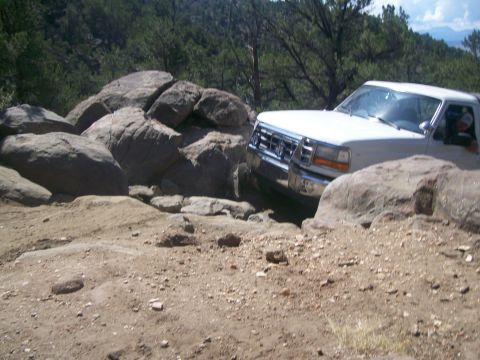 1993 Ford Bronco - A white Ford truck maneuvers through a rocky off-road course.