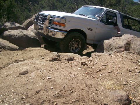 1993 Ford Bronco - White 1993 Ford Bronco is shown off-roading on a rocky trail.