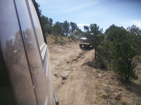1993 Ford Bronco - Two vehicles navigate a challenging off-road trail under a clear blue sky.