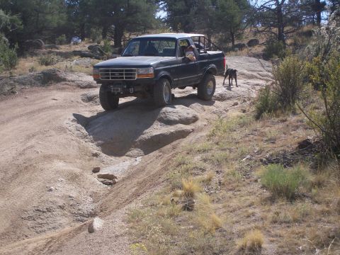 1993 Ford Bronco - This dark blue Ford Bronco navigates a challenging rocky trail, demonstrating its off-road capabilities.
