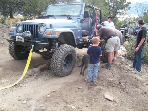 1993 Ford Bronco - People gathered around a blue Jeep Wrangler on a dirt trail, with another vehicle visible behind it.