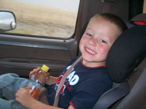 1993 Ford Bronco - Child rides in a car seat, holding a drink and looking out the window.