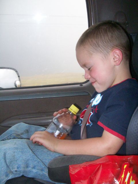 1993 Ford Bronco - A young boy sits in the passenger seat of a vehicle, holding a bottle of orange liquid.