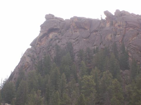 1993 Ford Bronco - A natural rock formation on a cliff face resembles a human profile, with a dense forest below.