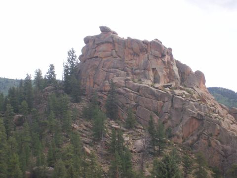 1993 Ford Bronco - A vast rock formation dominates the landscape, surrounded by scattered pine trees on a rocky slope.