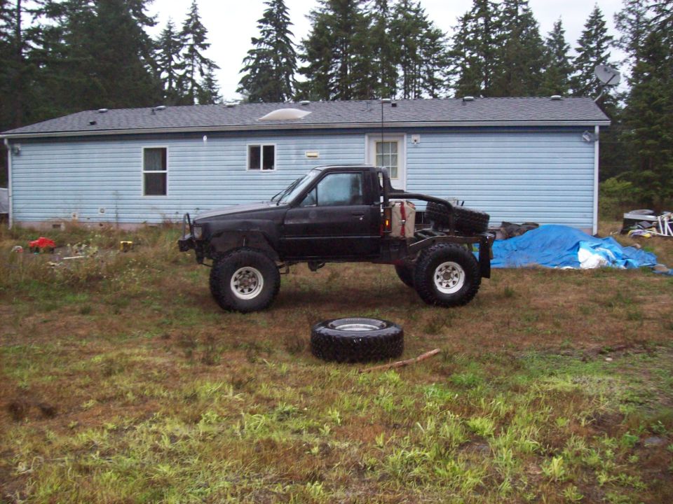 Black 1985 Toyota Pickup with large tires and flatbed