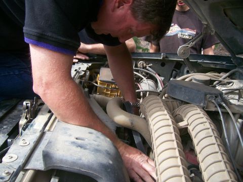 1993 Ford Bronco - Mechanic works on the engine of a 1993 Ford Bronco.