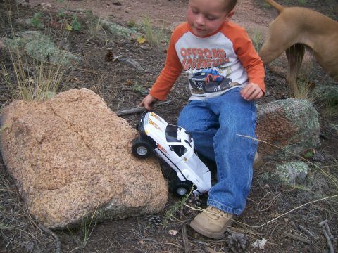 1993 Ford Bronco - A boy plays with a toy truck outdoors near rocks and dry grass.