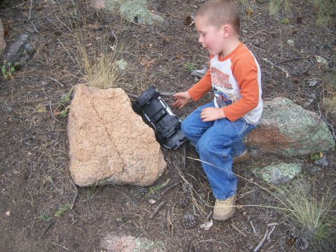 1993 Ford Bronco - A young boy plays with a toy truck in a wooded, rocky area.