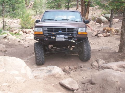1993 Ford Bronco - A brown Ford Bronco navigates a rocky trail, its off-road capabilities.