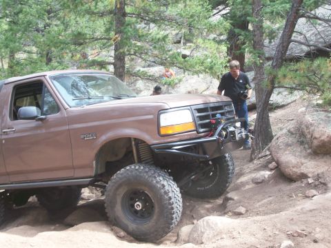 1993 Ford Bronco - A modified Ford Bronco tackles a challenging off-road course with spectators nearby.