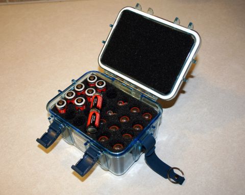 1984 Ford Bronco - A clear blue case holds multiple batteries and small components, organized within black foam padding.