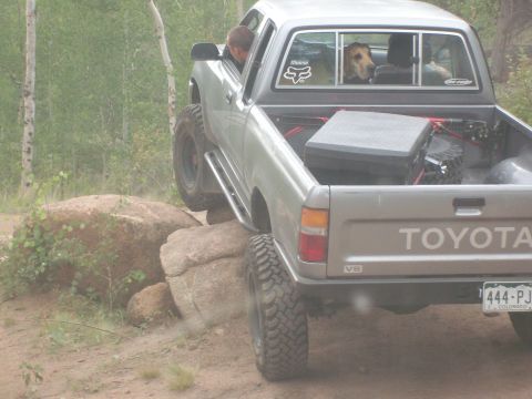 1993 Ford Bronco - A Toyota pickup truck navigates a rocky trail with a dog looking out the back window.
