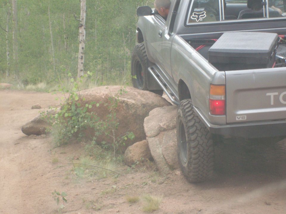 Silver Toyota pickup truck with large tires navigating over rocks