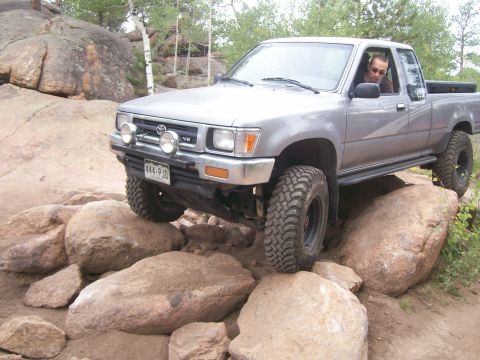 1993 Ford Bronco - This Toyota pickup is tackling a challenging rocky terrain, with its tires carefully placed on boulders.