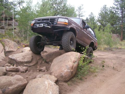 1993 Ford Bronco - Brown 1993 Ford Bronco navigating a rocky off-road course.